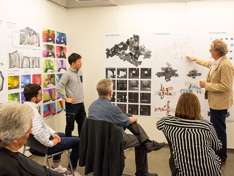 Students and faculty review work on a pin-up wall at a Final Review in the Hinman Research Building.