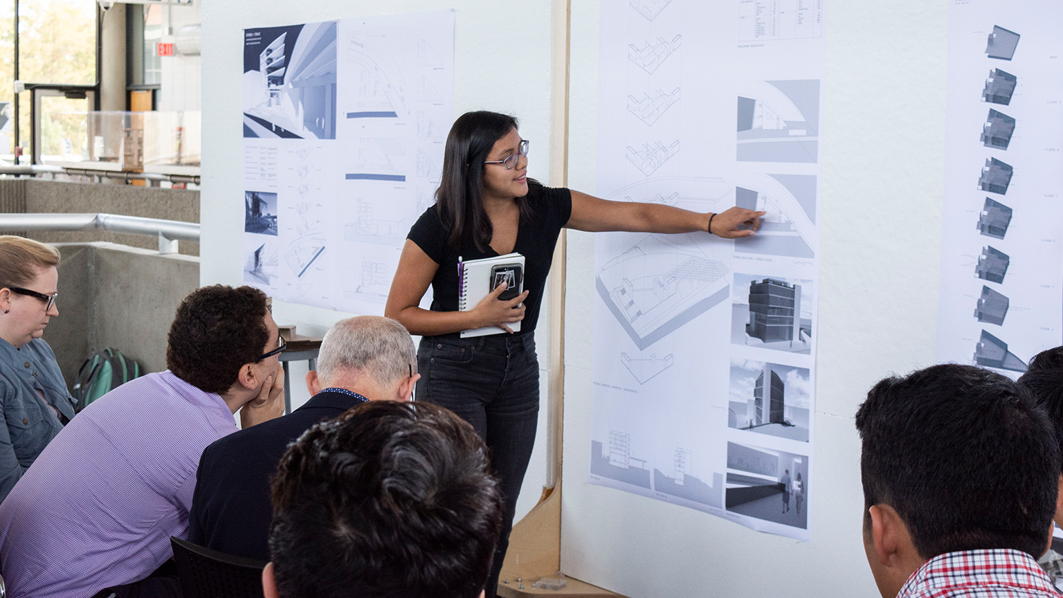 Student presenting a project in the Architecture West third floor atrium for a Junior Studio review.
