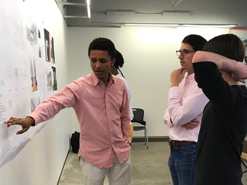 A students points to their project pinned up in the Hinman Research Building during a review with local professionals.