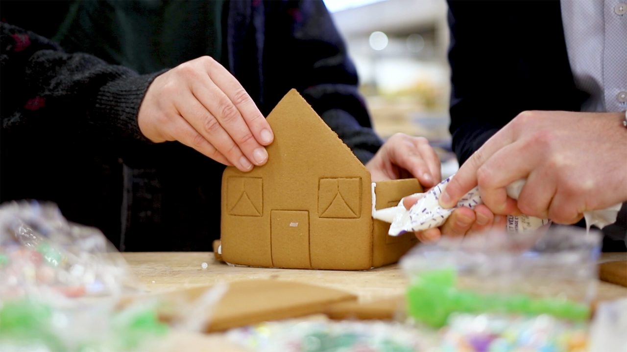 Hands decorate a gingerbread house